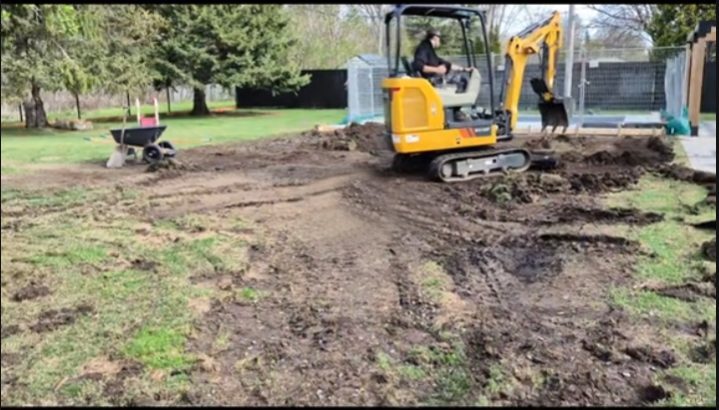 Mini-excavatrice nivelant le sol d’une cour arrière lors d’un terrassement